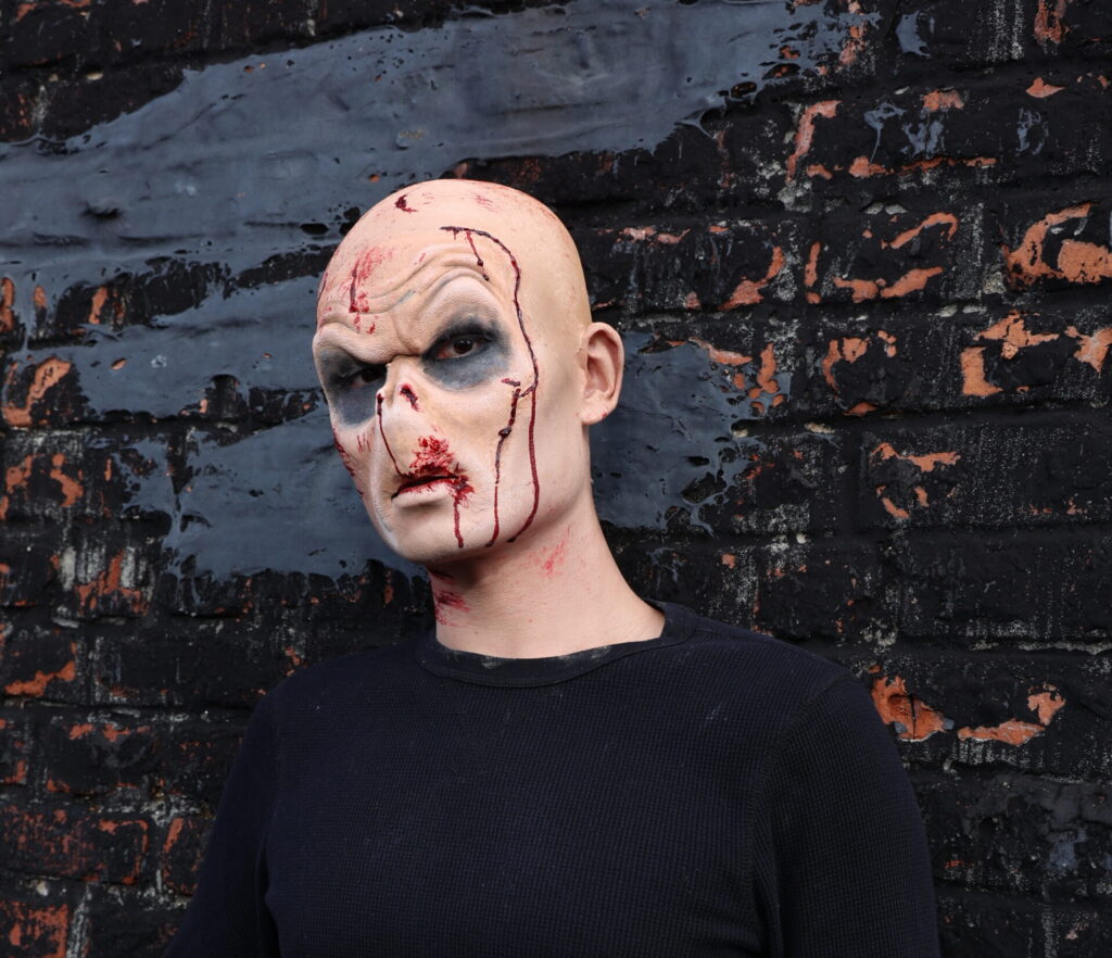 Bald person with bloody horror face makeup